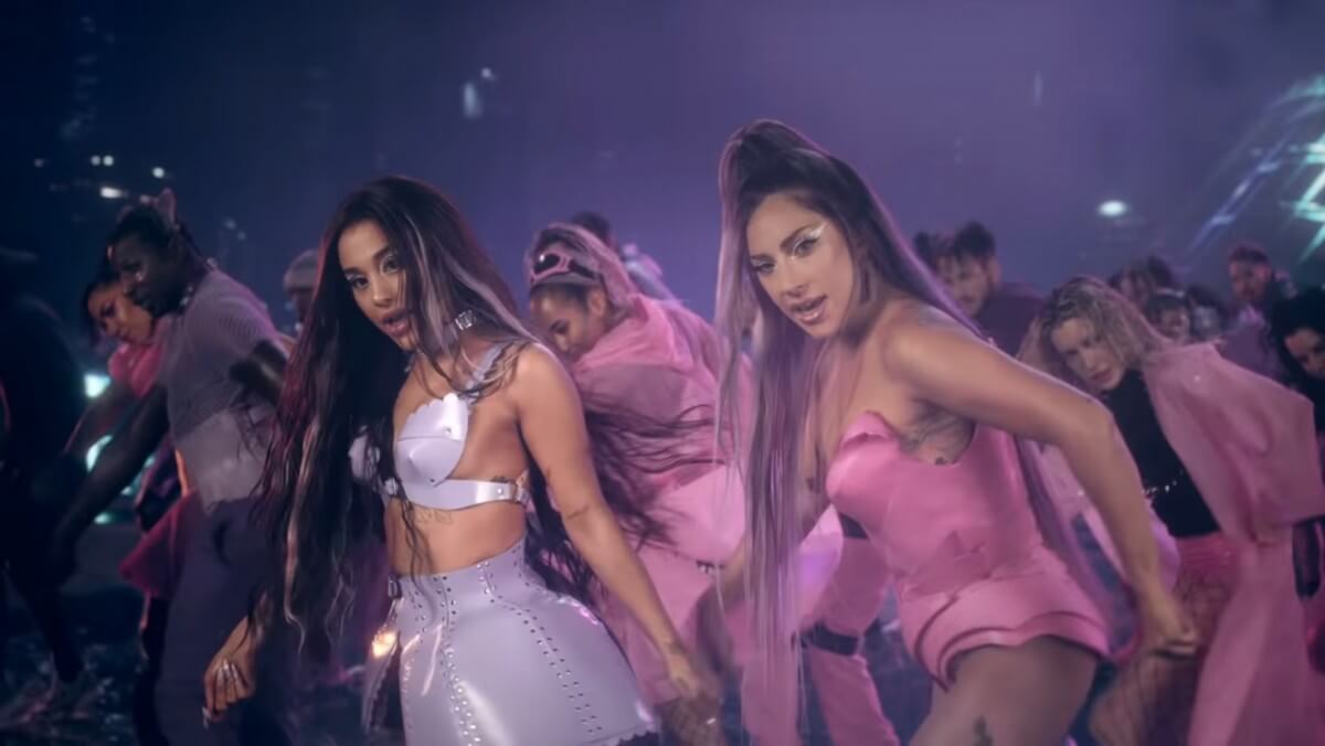 Ariana Grande dengan outfit silver dan Lady Gaga dengan outfit pink dalam musik video Rain on Me